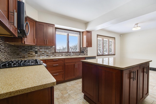 kitchen featuring tasteful backsplash, stovetop, a sink, and a center island