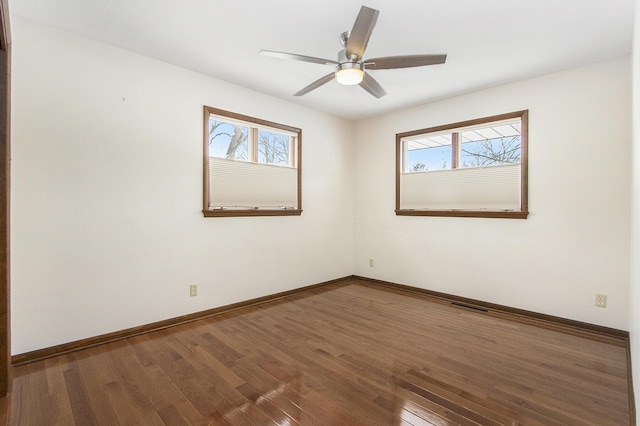 spare room featuring a healthy amount of sunlight, visible vents, baseboards, and wood finished floors