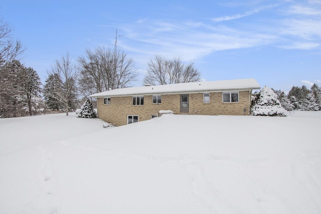 snow covered back of property featuring brick siding