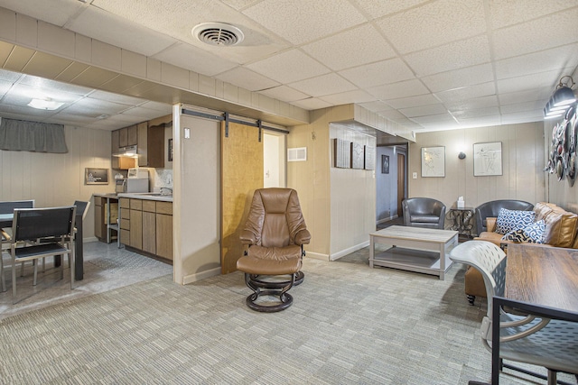 living area with a paneled ceiling, a barn door, visible vents, and light colored carpet