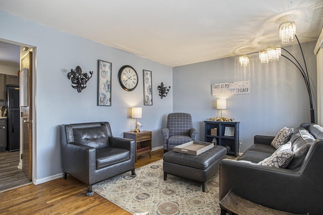 living room featuring a chandelier, wood finished floors, and baseboards