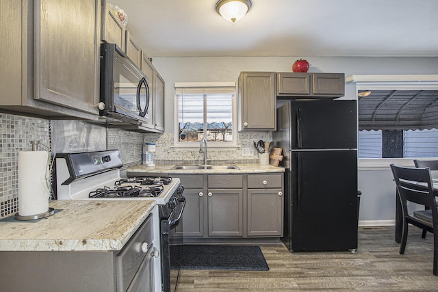 kitchen with dark wood-style floors, light countertops, a sink, and black appliances