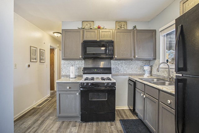 kitchen featuring dark wood-style flooring, a sink, visible vents, backsplash, and black appliances