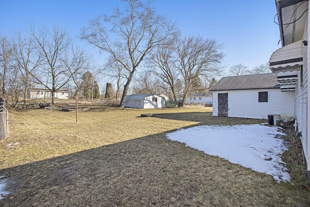 view of yard featuring an outbuilding, cooling unit, fence, and a storage unit