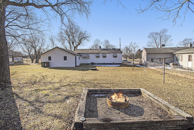 exterior space featuring a garden, an outdoor fire pit, fence, and a lawn