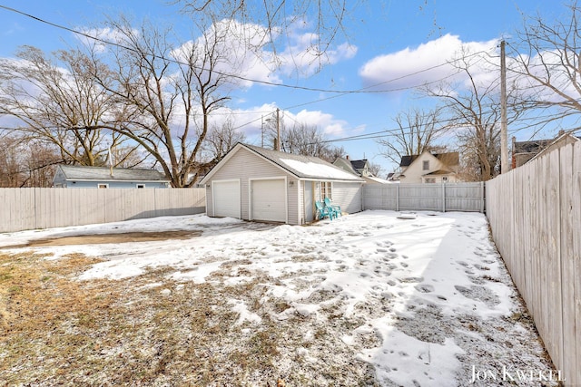 yard covered in snow featuring a garage, a fenced backyard, and an outdoor structure