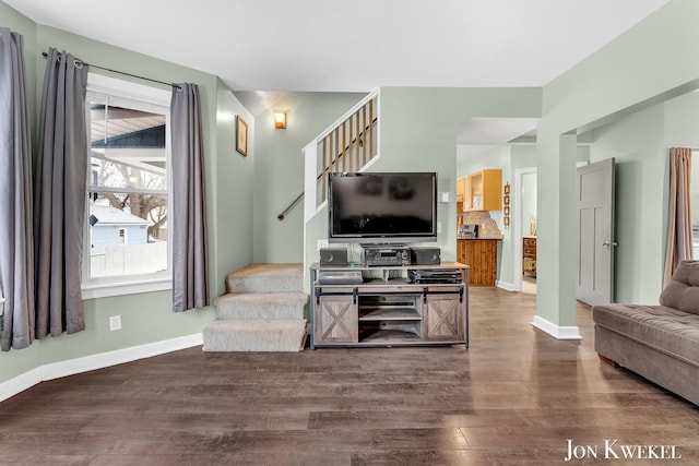 living room featuring stairs, baseboards, and wood finished floors