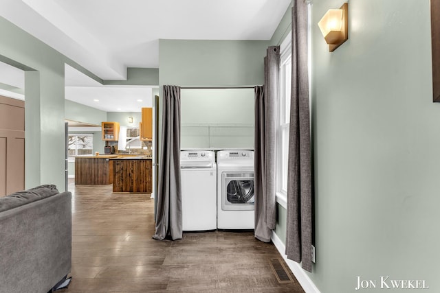 laundry area featuring laundry area, visible vents, wood finished floors, and washing machine and clothes dryer