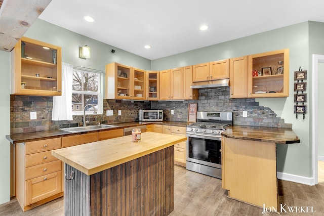 kitchen with glass insert cabinets, a center island, wood counters, and stainless steel gas range oven