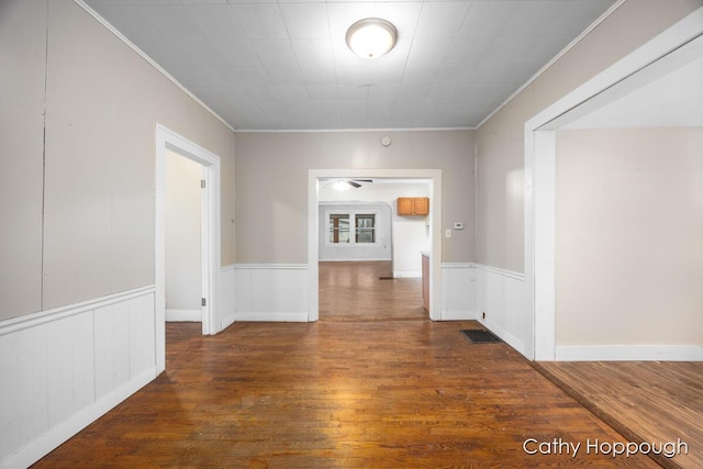 interior space with ornamental molding, wainscoting, visible vents, and wood finished floors