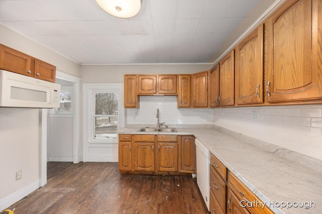 kitchen featuring white appliances, a sink, light countertops, brown cabinets, and dark wood finished floors