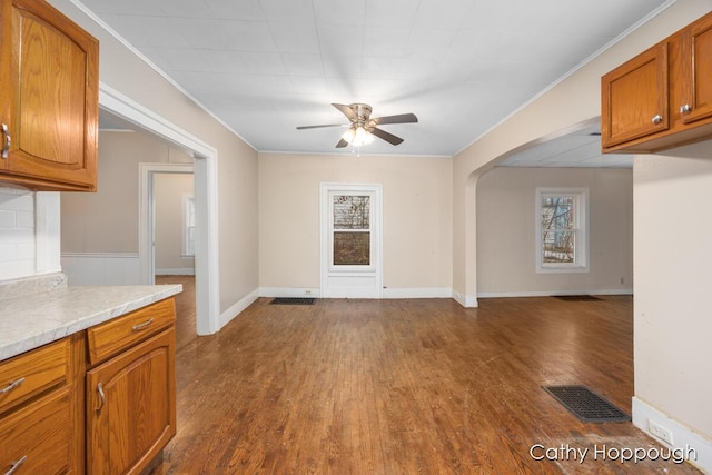 interior space with visible vents, arched walkways, a ceiling fan, dark wood-type flooring, and crown molding