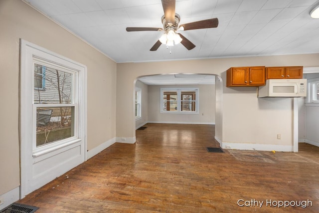 interior space featuring baseboards, visible vents, arched walkways, and wood finished floors