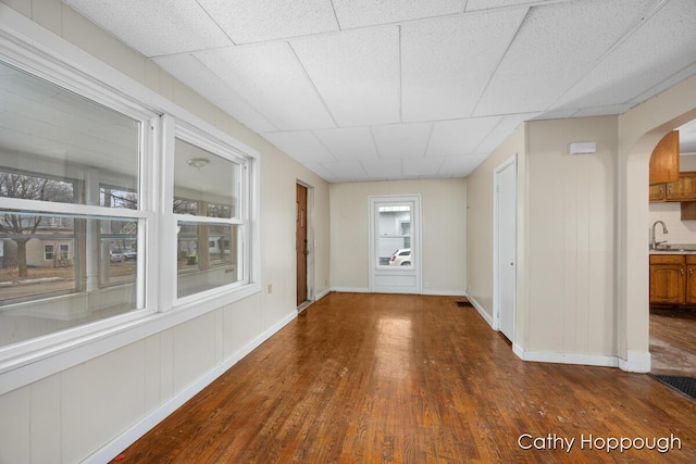 interior space with arched walkways, plenty of natural light, a sink, and dark wood finished floors