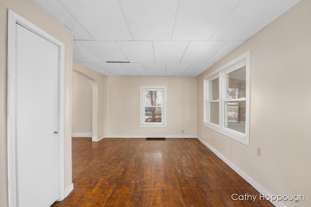 spare room with wood-type flooring, visible vents, arched walkways, and baseboards