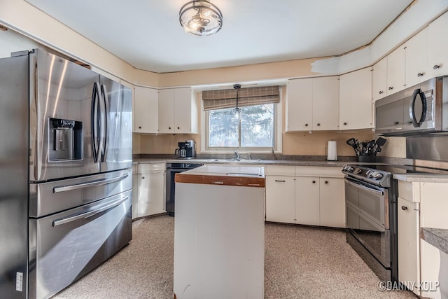 kitchen featuring hanging light fixtures, white cabinetry, appliances with stainless steel finishes, and a sink