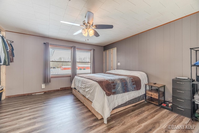 bedroom with ceiling fan, wood finished floors, and baseboards