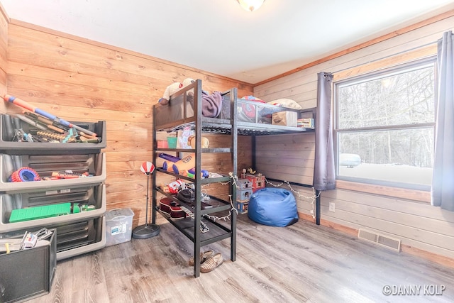 bedroom featuring wood walls, visible vents, and wood finished floors