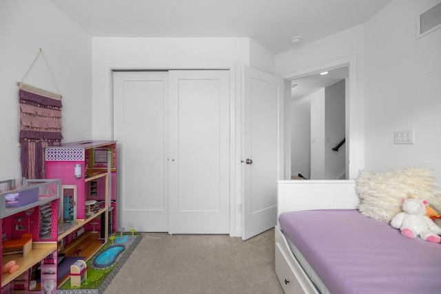 bedroom with a closet, visible vents, and light colored carpet