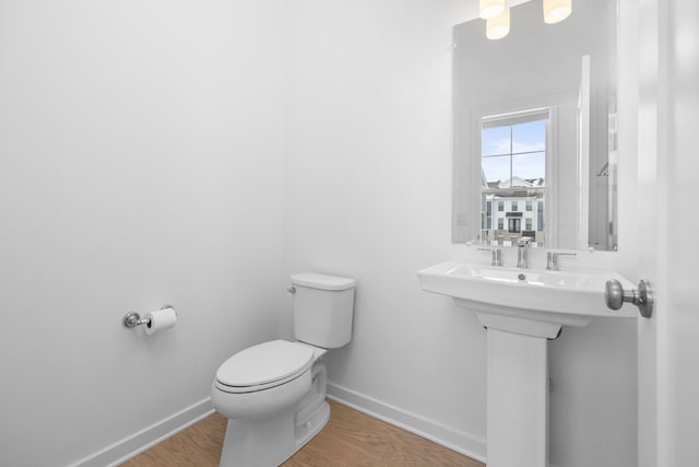 bathroom with baseboards, toilet, and wood finished floors