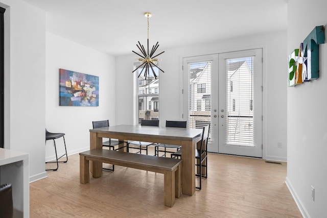 dining area with baseboards, visible vents, french doors, light wood-type flooring, and a notable chandelier