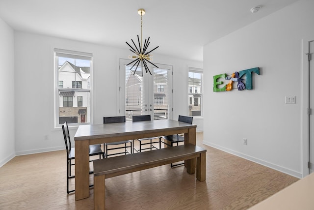 dining area with a chandelier, french doors, light wood-style flooring, and baseboards