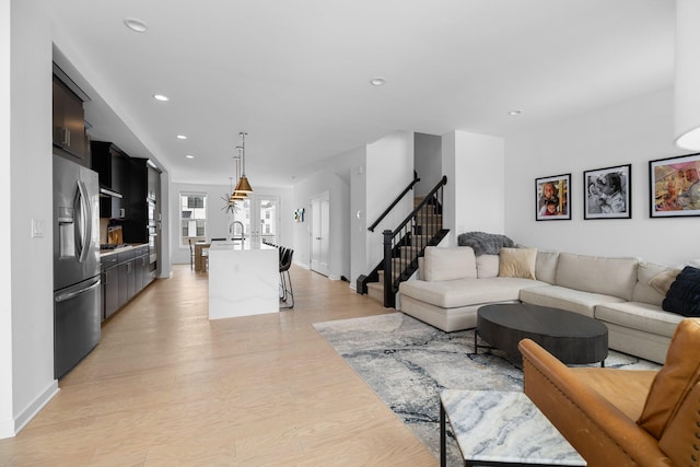 living area with light wood-style floors, stairway, and recessed lighting