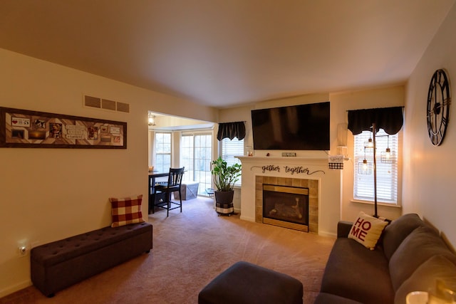 carpeted living room featuring visible vents and a tiled fireplace