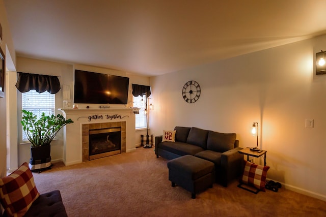 living area with light carpet, a tiled fireplace, and baseboards