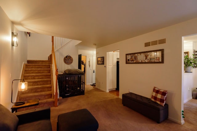 living room with light colored carpet, visible vents, baseboards, and stairs