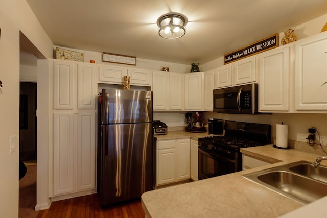 kitchen featuring freestanding refrigerator, light countertops, black range with gas cooktop, and a sink