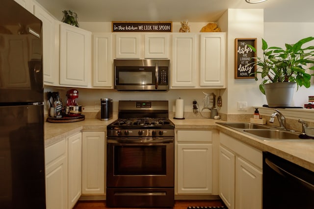 kitchen with light countertops, a sink, and black appliances