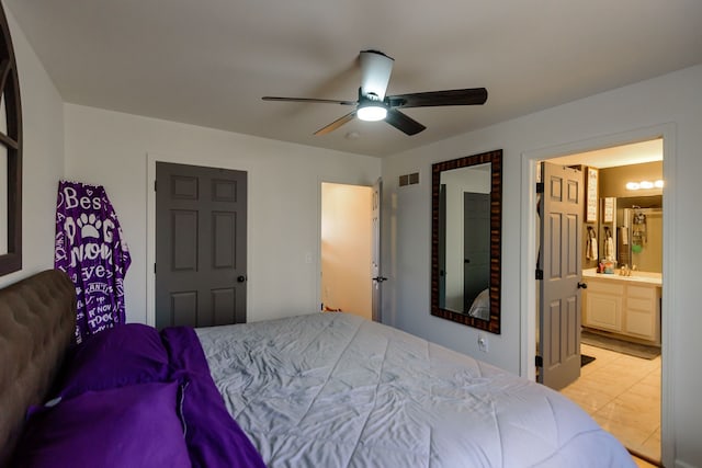 bedroom featuring light tile patterned flooring, visible vents, ceiling fan, and ensuite bathroom