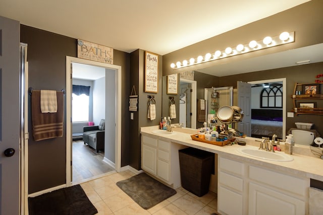 ensuite bathroom featuring a sink, double vanity, connected bathroom, and tile patterned floors