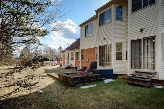 back of property with entry steps, central AC, and a lawn