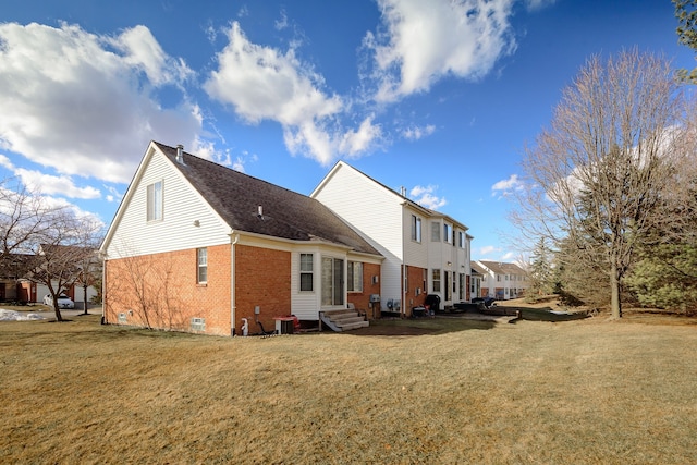 rear view of property featuring entry steps, central AC, a lawn, and brick siding