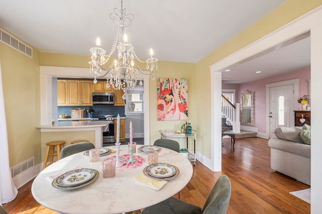 dining area with visible vents, stairs, baseboards, and wood finished floors