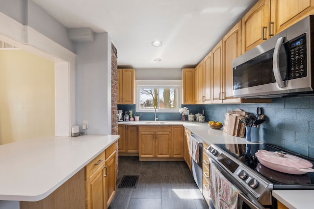 kitchen with a sink, backsplash, appliances with stainless steel finishes, and light countertops