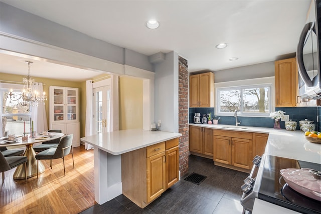 kitchen featuring stainless steel appliances, a sink, light countertops, pendant lighting, and tasteful backsplash