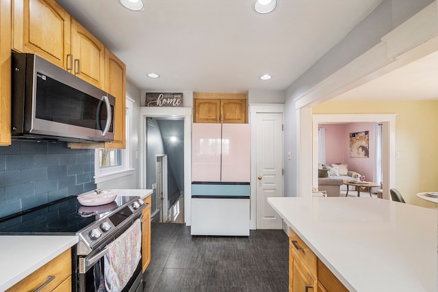 kitchen with recessed lighting, stainless steel appliances, light countertops, dark wood-type flooring, and tasteful backsplash