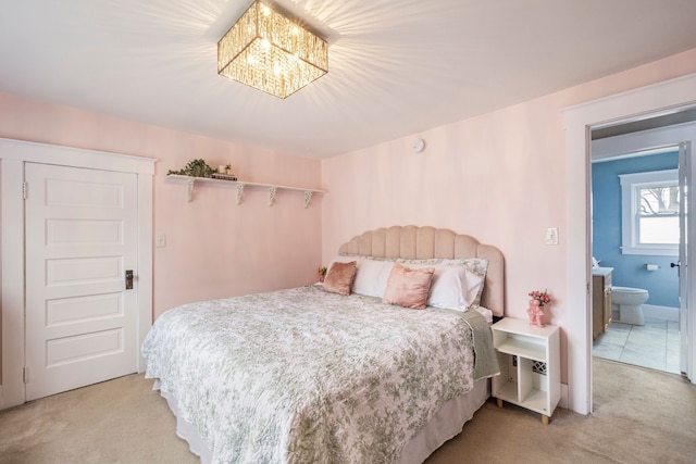 bedroom featuring light carpet, an inviting chandelier, and ensuite bathroom