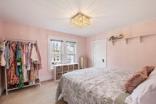 bedroom featuring an inviting chandelier, light colored carpet, and baseboards