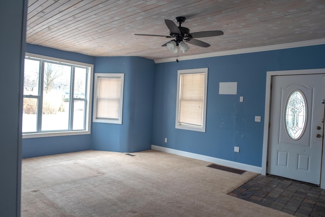 carpeted entrance foyer with ceiling fan, wood ceiling, visible vents, baseboards, and ornamental molding