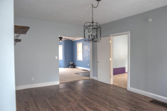 interior space with a textured ceiling, dark wood-type flooring, visible vents, and baseboards