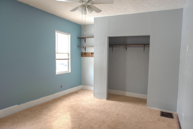 unfurnished bedroom featuring baseboards, visible vents, light colored carpet, a textured ceiling, and a closet