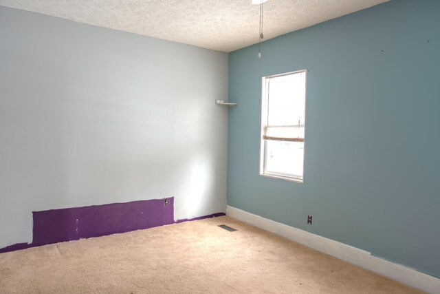 unfurnished room featuring baseboards, carpet, visible vents, and a textured ceiling