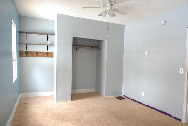 unfurnished bedroom featuring visible vents, a ceiling fan, light colored carpet, a textured ceiling, and a closet