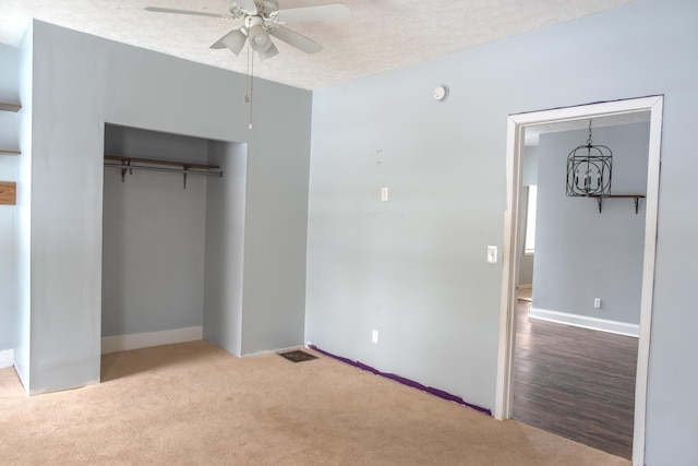 unfurnished bedroom with a textured ceiling, a closet, light carpet, and a ceiling fan