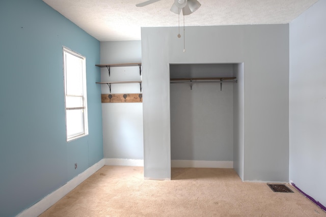 unfurnished bedroom featuring light carpet, baseboards, visible vents, a textured ceiling, and a closet