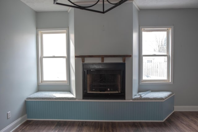 unfurnished living room with dark wood-style flooring, a fireplace, and baseboards